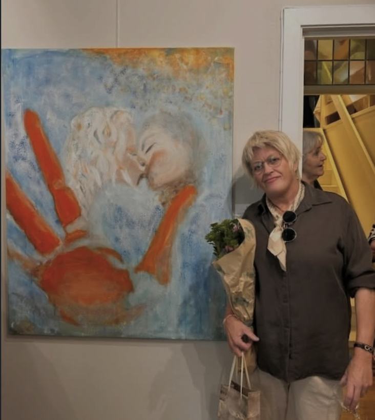 Trine Midtlie Elmholt med blomsterbukett ved siden av maleriet Kysset i et galleri.